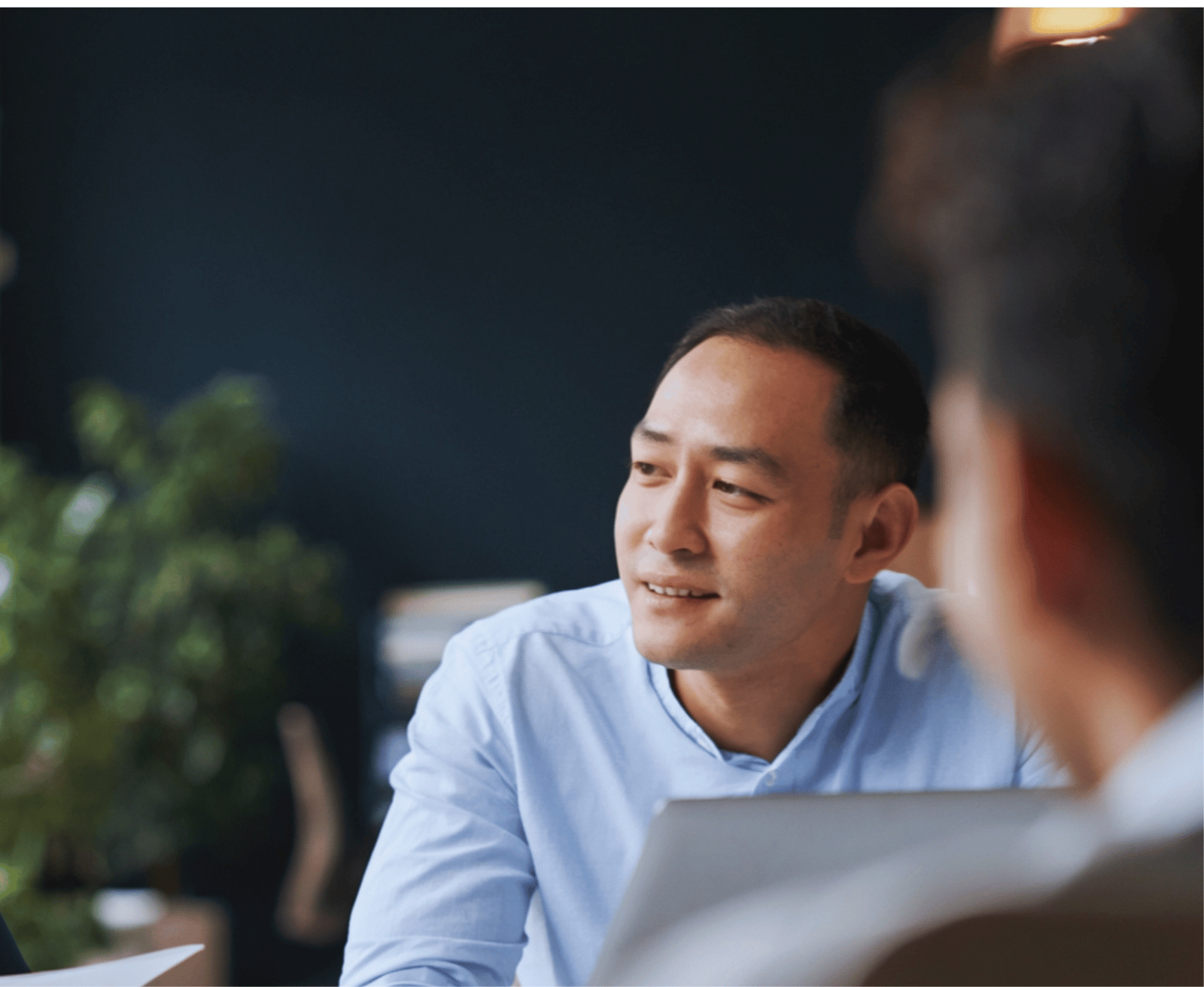 A professional in a light blue shirt in conversation across a table